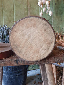 Antique German apothecary jar (brown with maroon stripes) on a rustic stool. It is styled with a black bucket of lavender and a vineyard basket against a sage green planked door.
