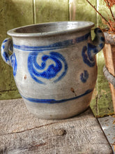 Load image into Gallery viewer, Grey and blue Betschdorf confit pot sitting on a low, weathered rustic farmhouse stool. In the background is a rustic farmhouse door painted in sage green, with sunlight streaming in from the left.