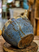 Load image into Gallery viewer, A rustic handmade  primitive antique French cruche with a blue and brown glaze, displayed on a wooden stand in a softly blurred indoor setting.