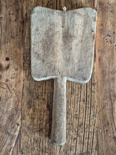 Load image into Gallery viewer, Antique Hungarian oak chopping board with a distinctive tulip-shaped outline and long handle, displayed with cheese and rustic food on a weathered wooden table. The solid oak board has a few historic cutting scars and natural aged wood texture. The board measures 13 inches (33 cm) long including the handle, resting on a weathered wood plank background.