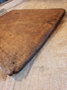 Antique French Rustic Farmhouse Bread Board Cutting Board sitting on top of a French Linen Flour sack on top of a primitive wooden french farm house table in the Dusty Gems Interiors Nanntwich shop