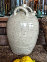 Load image into Gallery viewer, A 19th-century French walnut oil jar in buff terracotta with a thick cream tin glaze, showing a rustic, time-worn patina and simple provincial form.