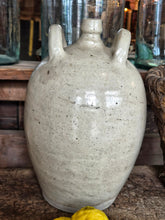 Load image into Gallery viewer, A 19th-century French walnut oil jar in buff terracotta with a thick cream tin glaze, showing a rustic, time-worn patina and simple provincial form.