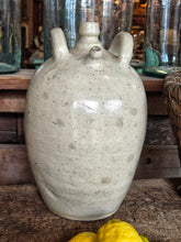 Load image into Gallery viewer, A 19th-century French walnut oil jar in buff terracotta with a thick cream tin glaze, showing a rustic, time-worn patina and simple provincial form.