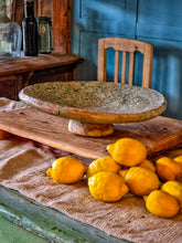 Load image into Gallery viewer, A heavy, hand-formed Moroccan Tamegroute footed serving dish with a soft cream ground and a delicate green splatter glaze. The shallow pedestal bowl features a rough, textured, salt-fired crystalline finish and is styled filled with bright lemons against a backdrop of weathered timber and rustic country-house furniture.