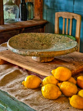 Load image into Gallery viewer, A heavy, hand-formed Moroccan Tamegroute footed serving dish with a soft cream ground and a delicate green splatter glaze. The shallow pedestal bowl features a rough, textured, salt-fired crystalline finish and is styled filled with bright lemons against a backdrop of weathered timber and rustic country-house furniture.