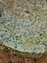 Load image into Gallery viewer, A heavy, hand-formed Moroccan Tamegroute footed serving dish with a soft cream ground and a delicate green splatter glaze. The shallow pedestal bowl features a rough, textured, salt-fired crystalline finish and is styled filled with bright lemons against a backdrop of weathered timber and rustic country-house furniture.
