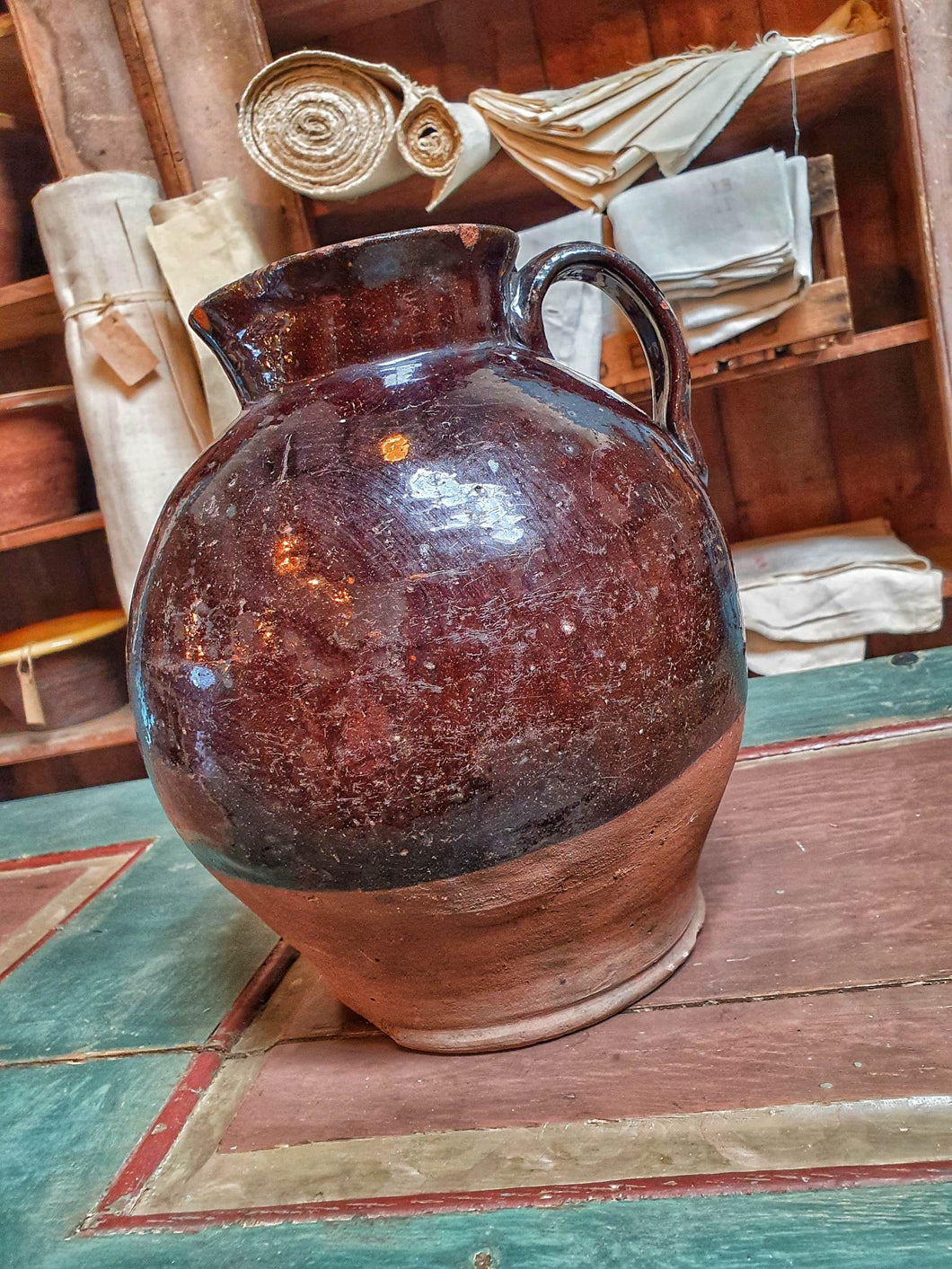 Antique Welsh Buckley Black Pottery Jug Rustic vernacular North wales flintshire jug sitting ontop of swedish painted marrage chest with french vintage linen in the background on french farmhouse rustic shelving in the dusty Gems interiors shop 