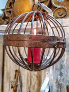Antique Iron globe Candle Gimbal Lantern Primitive Rustic Farmhouse decor hanging on painted iron hook with primited white painted farmhouse door in background dusty gems interiors nantwich