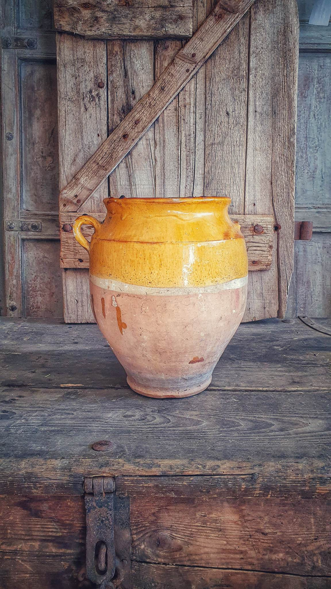 Antique French Large Confit pot Rustic Farmhouise mustard Glaze  Terracotta body sitting infront of french country primitive wooden shutters in the Dusty Gems interiors nantwich shop 