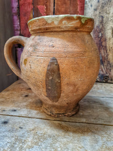 French Antique Rustic Confit Pot primitive Farmhouse kitchen olive pot sitting on french rustic country table with terracotta dairy bowl and large french cutting board and french mint plant in old pot all agaist a background of red painted rusic panel wall with flaking paint dusty gems interiors nantwich