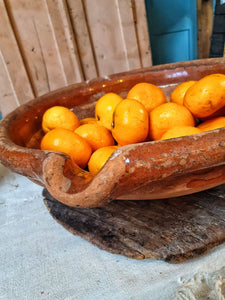 French Antique 19th Century Gassoutlet Dairy Bowl rustic Farmhouse provence pottery brown glazed terracotta sitting on red painted french farmhouse bench primitive wooden kitchen behind bowl is filled with oranges dusty gems interiors nantwich