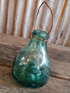 Antique Spanish green  Glass Wasp Trap Rustic French Country cottage Garden sitting on a wooden rustic french farmhouse table with a green glass french storage jar with wellow flowers in it  French country garden dusty gems interiors nantwich